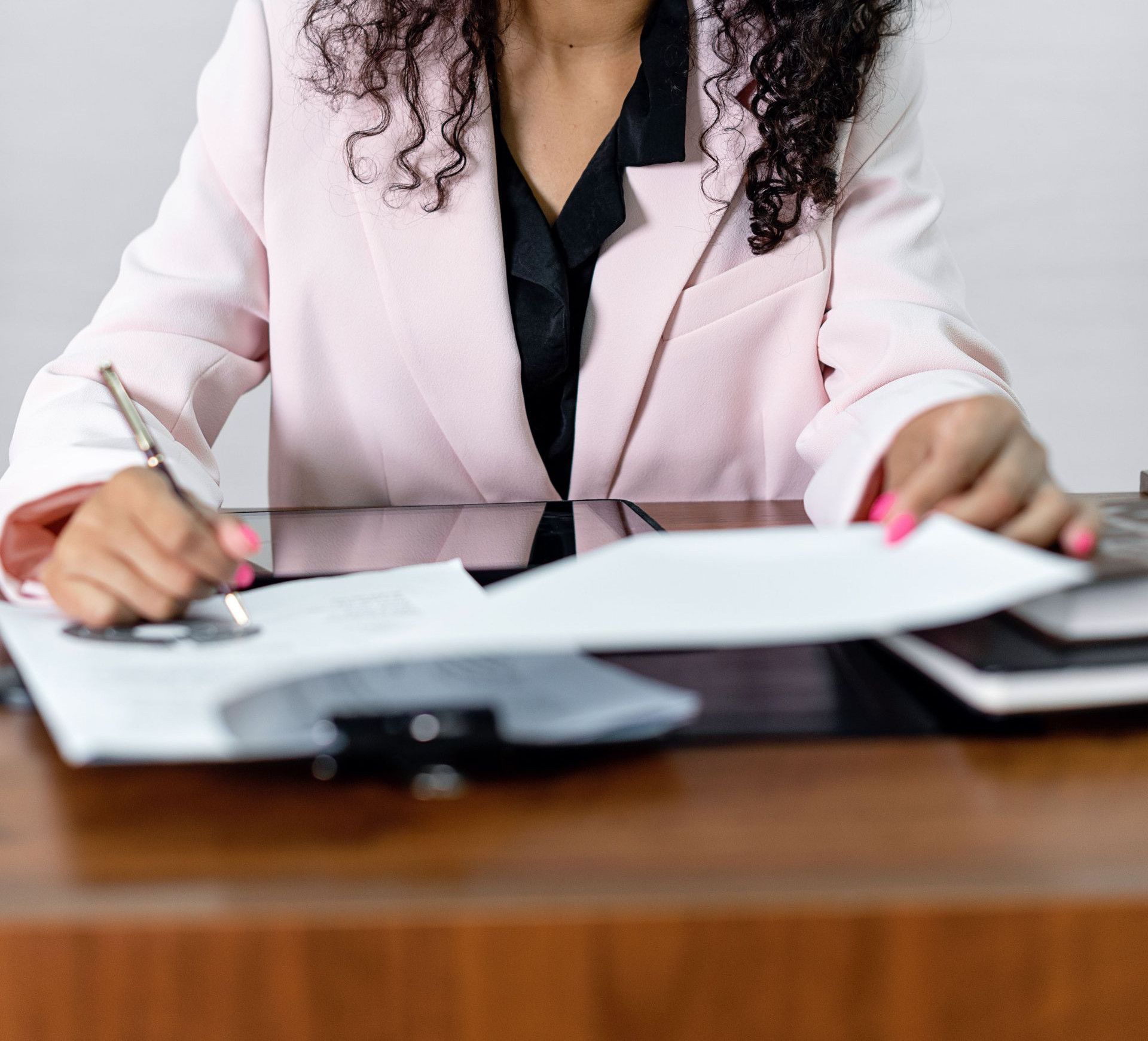 Focused businesswoman signing important documents at her office desk.